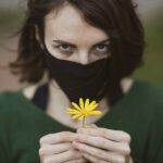 woman in green shirt holding yellow flower